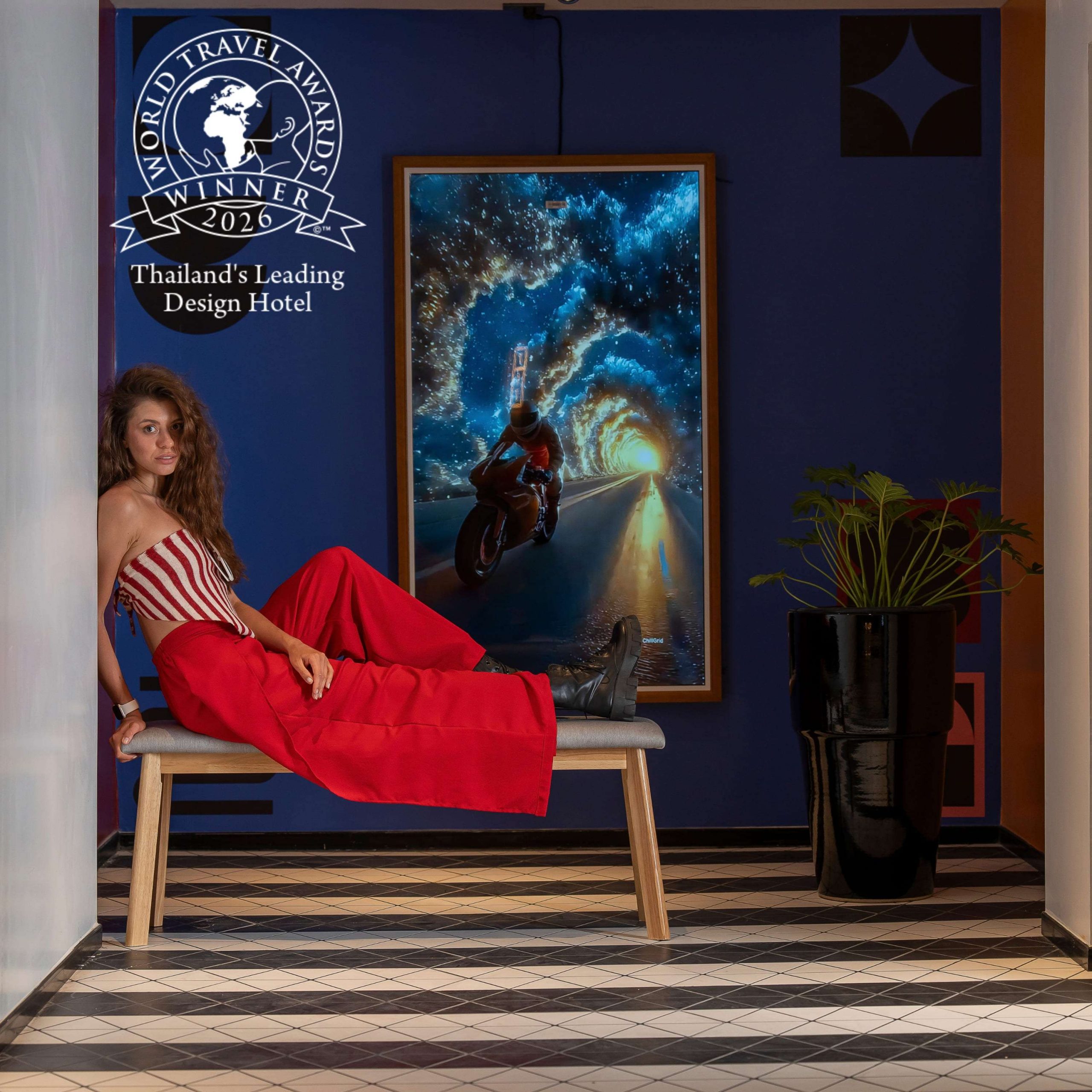 Guest relaxing in a bold blue TRIBE Phuket Patong space with the World Travel Awards 2026 winner badge